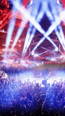 a crowd of people at a concert with blue lights coming out of the stage