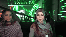 a woman wearing a hijab sits next to another woman