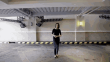 a woman is standing in a parking garage with a yellow and black stripe on the floor