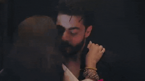 a man and a woman are kissing in a room .