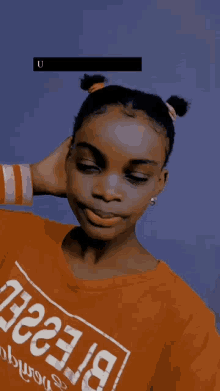 a girl wearing an orange shirt that says ' uyu mtot ' on the bottom