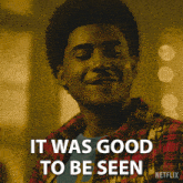 a man in a plaid shirt is smiling with the words it was good to be seen behind him