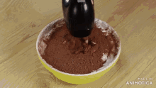 a yellow bowl filled with cocoa powder is being mixed with a mixer and the words made in animotica are on the bottom