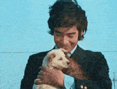 a man in a suit is holding a puppy in his hands