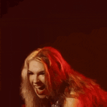 a woman in a red dress is playing a red guitar on a stage .