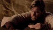 a man with a beard is laying down on a bed with his hand on his chin .