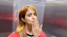 a woman blowing a kiss with her hand on her face