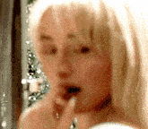 a woman is brushing her teeth in front of a mirror in a bathroom .