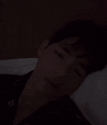a man is sleeping on a bed with his eyes closed in the dark .