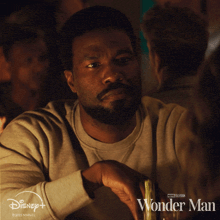 a poster for wonder man shows a man sitting at a table with a drink