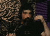 a man is singing into a microphone with a tree on his shirt behind him