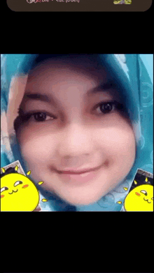 a woman wearing a blue hijab and a yellow sticker on her face is smiling
