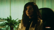 a woman wearing glasses sits in a chair in front of a screen that says bull