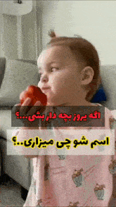 a little girl in a pink dress is eating a strawberry