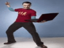 a man in a red shirt is holding a laptop computer while dancing .