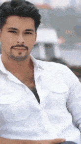 a man with a beard wearing a white shirt looks at the camera