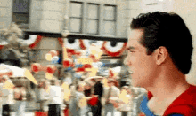 a man in a superman costume is standing in front of a crowd .