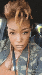 a woman with dreadlocks and a camouflage jacket is sitting in a car
