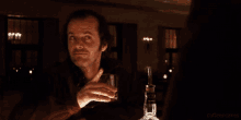 a man sitting at a table with a glass of whiskey and a bottle of whiskey