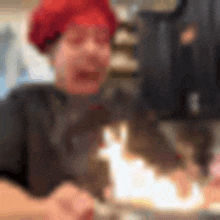 a woman wearing a red hat is sitting at a table with a cake on it .
