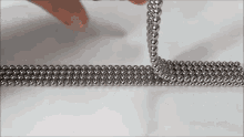 a person is playing with a bunch of metal balls on a table .