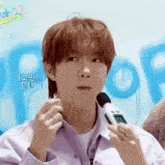 a man in a purple shirt is holding a microphone and making a funny face .