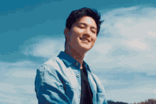 a young man wearing a blue shirt is smiling in front of a blue sky