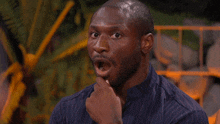 a man in a blue striped shirt is making a surprised face .