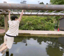 a person is hanging from a pipe over a body of water