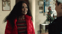 a woman with curly hair wearing a red jacket smiles at a man