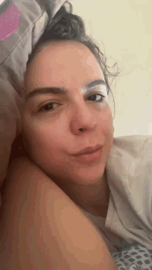 a close up of a woman laying in bed with a blanket on her head