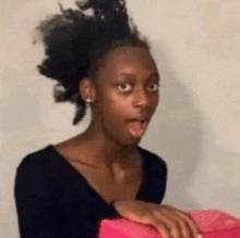 a woman with a surprised look on her face is holding a pink gift box .