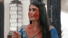 a woman with blood on her face is wearing a blue and white striped saree .