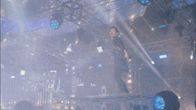 a man stands on a stage with a microphone in his hand in front of a blue light
