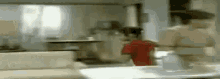 a blurry picture of a person standing in a kitchen .