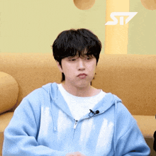 a man wearing a blue hoodie with the word st7 on the bottom right