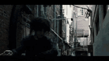 a man in a blue shirt is walking down a dark alley