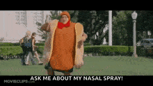 a man in a hot dog costume is standing in a grassy field .