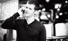 a man is standing in front of a building talking on a cell phone .