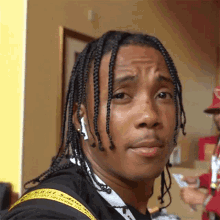 a close up of a man with braids wearing a black shirt that says off white on it