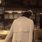 a person wearing headphones and a white jacket stands in a living room
