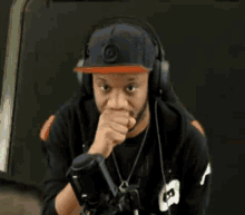 a man wearing headphones and a hat is pointing at the camera