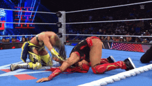 two women are wrestling in a wrestling ring and one of them is laying on the ground