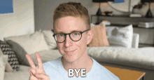 a man wearing glasses is giving a peace sign and the word bye is behind him .