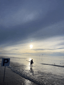 a man stands in the water near a sign that has the letter p on it