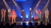 a group of people are dancing on a stage with blue lights