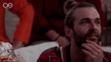 a man with a beard is sitting in front of a screen that says queen eye