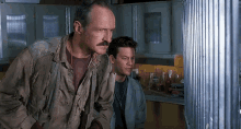 a man with a mustache is standing next to another man in a room