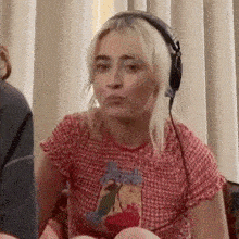a woman wearing headphones is sitting on a couch .