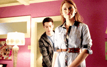 a man and a woman standing next to each other in a room with purple walls